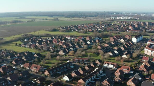 POV over a suburb in Germany with new buildings with factories of industrial city in background, aerial view