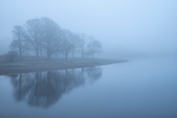 Stunning landscape image of misty Derwentwater in Lake District on cold Winter morning