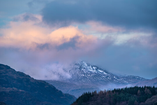 Majestic landscape image across Loch Lomond looking towards snow capped Ben Lui mountain peak in Scottish Highlands
