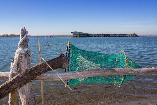 Marine background. Poles and green keepnet with the sea background. Old abandoned fishing net hanging on poles on the beach. Porto Caleri, Italy.