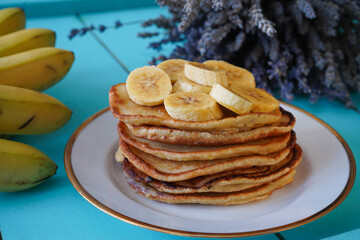 Delicious pancakes with banana and on blue wooden table. Breakfast time 