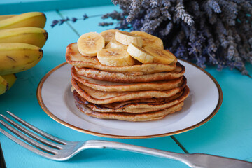 Delicious pancakes with banana and on blue wooden table. Breakfast time 