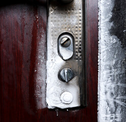 Frozen door lock with ice and snow close-up.