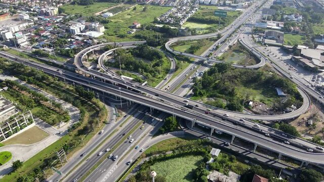 4K. Aerial view of road interchange or highway intersection with busy urban traffic speeding on the road. Junction network of transportation taken by drone.