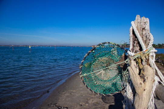 Marine background. Pole with hanging ropes and a green keepnet with the sea background. Porto Caleri beach, Italy in winter.