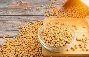 Soybeans in glass bowl with Soybeans pour from bag on wooden table background.Healthy food Concept.