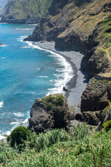 Fototapeta na wymiar Stoney beach with high cliffs on Madeira Island