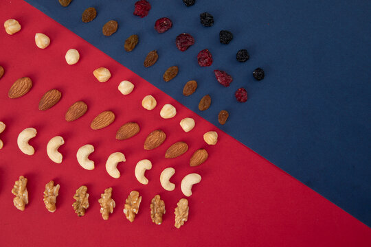 Top view of nuts and raisins assortment in a row isolated on red-blue background