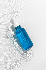 Blue cosmetic bottle on the water surface. Summer water pool fresh concept. Flat lay, top view.