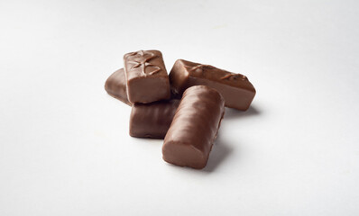 Five chocolates with milk chocolate on a white background for insulation. Sweets for tea.