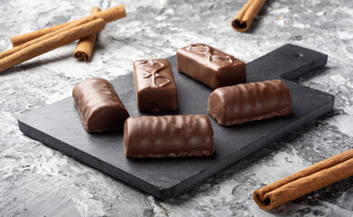 Five chocolates with milk chocolate on a dark background. Sweets for tea. Candy with cinnamon