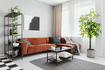 Trendy living room interior with brown corner sofa with black and white pillows and industrial...