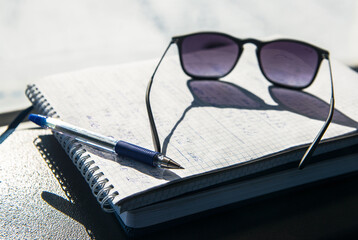 Pen, glasses, notepad on the dashboard in the car. Notes from road.