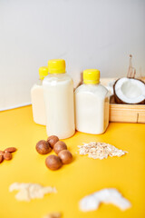 Alternative types of vegan milks in bottles on a yellow background