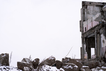 The remains of a ruined building with gray concrete rubble in the foreground against a gray sky....