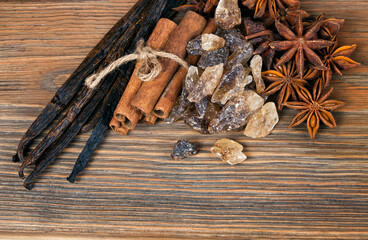 Cinnamon sticks, star anise and vanilla beans with crystals of brown sugar on a wooden background. Top view. Sweet spices concept.