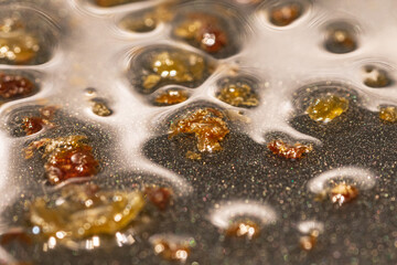 Macro shot of greaves of fries in oil in a pan.