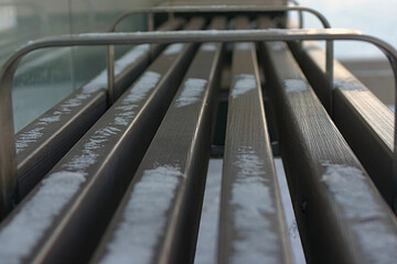 a snow-covered bench at a bus stop on a winter day