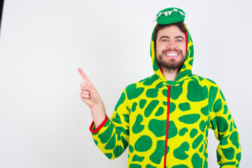 Young caucasian man wearing a pajama standing against white background looking at camera indicating finger empty space sales