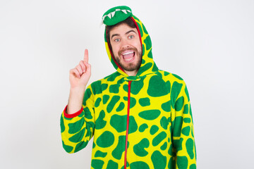 Young caucasian man wearing a pajama standing against white background holding finger up having idea and posing