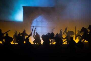 Medieval battle scene with cavalry and infantry. Silhouettes of figures as separate objects, fight between warriors on sunset foggy background.