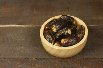 Close-up dried dates palm in wooden bowl on wooden background.