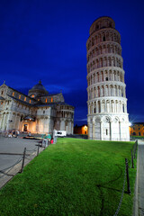 Illuminated Pisa Cathedral By Leaning Tower Against Blue Sky At Dusk