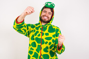 Fototapeta premium Young caucasian man wearing a pajama standing against white background imagine steering wheel helm rudder passing driving exam good mood fast speed