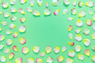 Beautiful rectangular pattern of pink and yellow rose petals and leaves on green paper background. Copy space for your text.