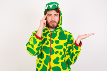 Fototapeta premium Young caucasian man wearing a pajama standing against white background confused and annoyed with open palm showing copy space and pointing finger to forehead. Think about it.
