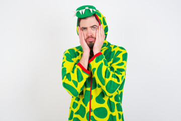 Fototapeta premium Young caucasian man wearing a pajama standing against white background Tired hands covering face, depression and sadness, upset and irritated for problem