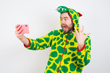 Wow!! excited Young caucasian man wearing a pajama standing against white background showing mobile phone with open hand gesture