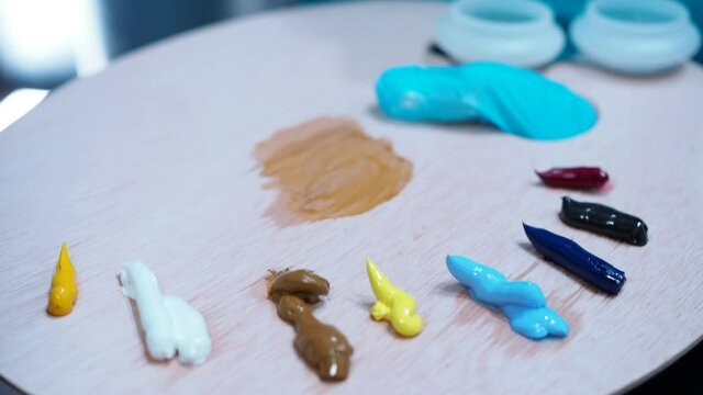 the girl takes the paint with a brush from the palette.