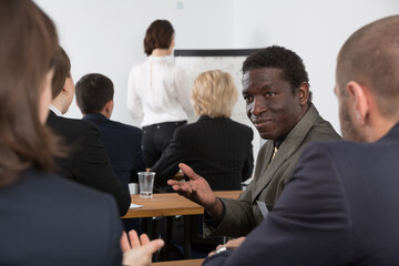 African American business man talking with people during conference in meeting room.
