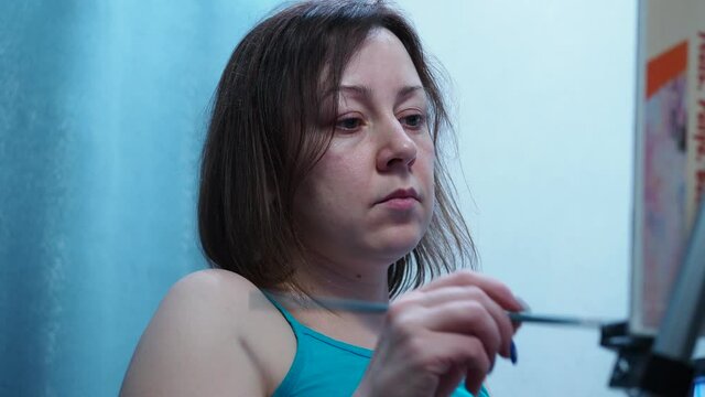 a girl draws a brush on a canvas standing on a tripod. home studio of fine arts. drawing lessons.