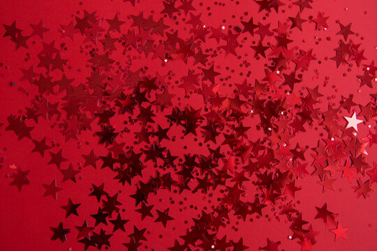 Red confetti in the form of stars on a red background