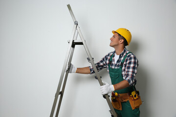 Professional builder with metal ladder on light background © New Africa