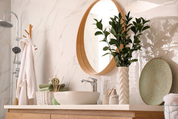 Vase with beautiful branches and toiletries near vessel sink in bathroom. Interior design