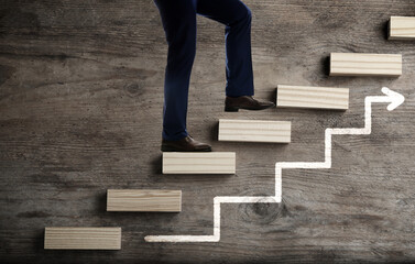 Businessman walking up stairs against wooden background, closeup. Career ladder concept