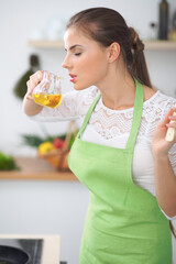 Young woman smelling the vegetable oil while enjoys cooking in the kitchen