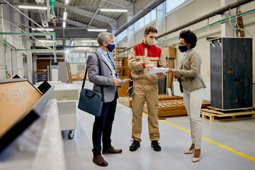 Fototapeta premium Company managers and leading carpenter analyzing reports at wood factory during coronavirus pandemic.