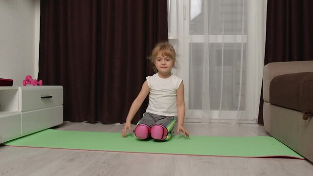 Fit little child kid training gymnastics fitness twine stretching workout on mat. Healthy lifestyle, active leisure at home. Children girl in sportswear making sport exercises, warming up cardio