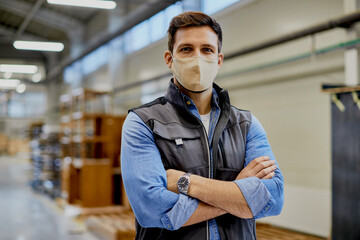Portrait of confident carpenter of woodworking factory with protective face mask.