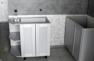 Lower custom kitchen cabinets installation with a furniture facades mdf. Gray modular kitchen from chipboard material on a various stages of installation. A frame furniture fronts mdf profile.