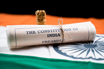 Indian constitution or Bharatiya Savidhana preamble old scattered text paper placed on Indian flag...