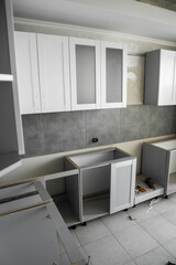 Fototapeta na wymiar Custom kitchen cabinets installation with a furniture facades mdf. Gray modular kitchen from chipboard material on a various stages of installation. A frame furniture fronts mdf profile.