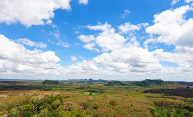 White clouds in blue sky over green mountains covered with rainforests trees