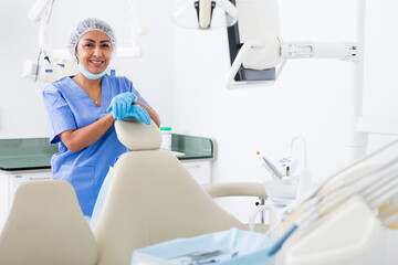 Portrait of successful professional woman dentist standing in blue uniform in modern medical dental office