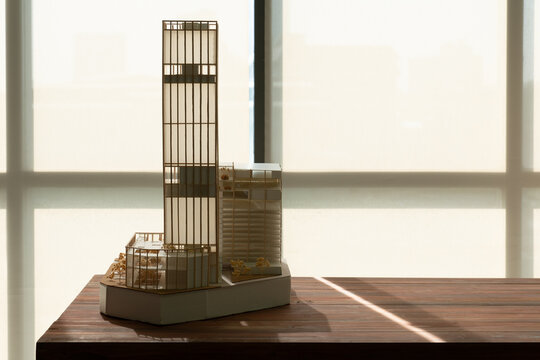 high rise building model made of wood and paper placing on table near window