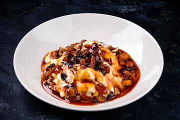 sweet dessert with pecan, caramel and baked apple on dark background